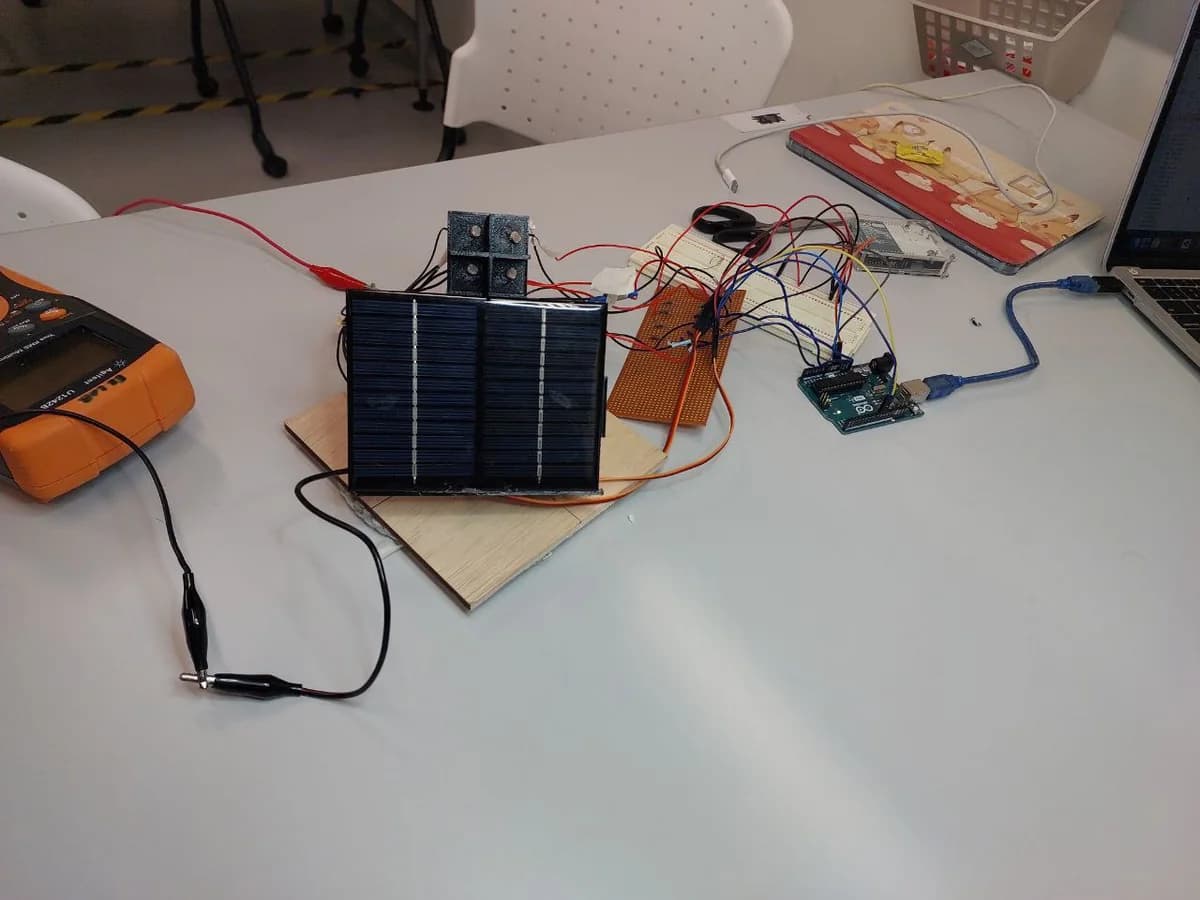 A solar panel prototype on a worktable, wired to light sensors, a breadboard, and an Arduino board.