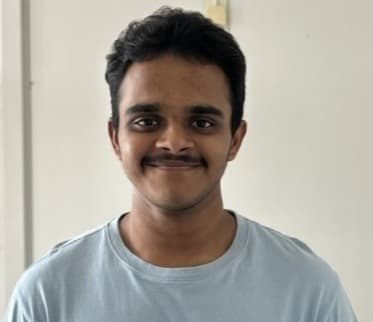 Portrait of Guru Prasath in a light blue shirt, looking toward the camera.
