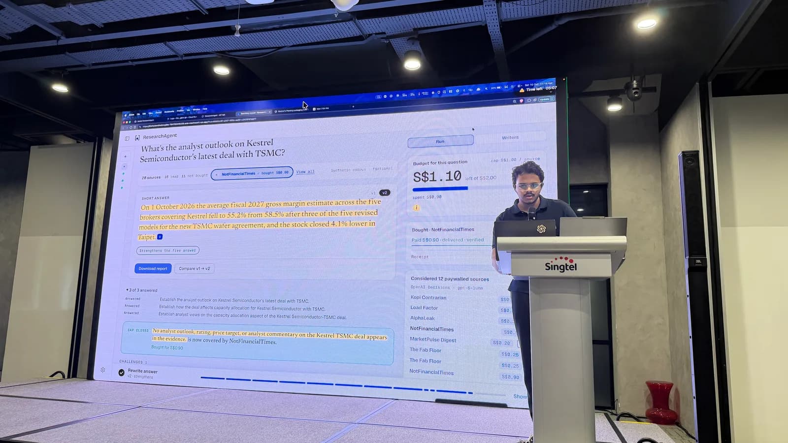 ResearchAgent’s answer and spending budget projected beside a presenter at the Singtel podium.